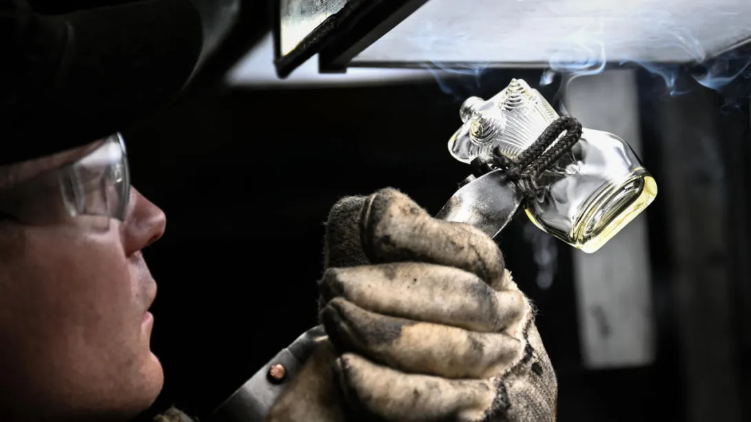 A la verrerie Pochet du Courval en Seine-Maritime, un salarié en train d'examiner un flacon de parfum en cours de fabrication, le 28 mars 2025 © LOU BENOIST / AFP